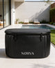 Black Nørva ice bath on a patio with a pool and chairs in the background